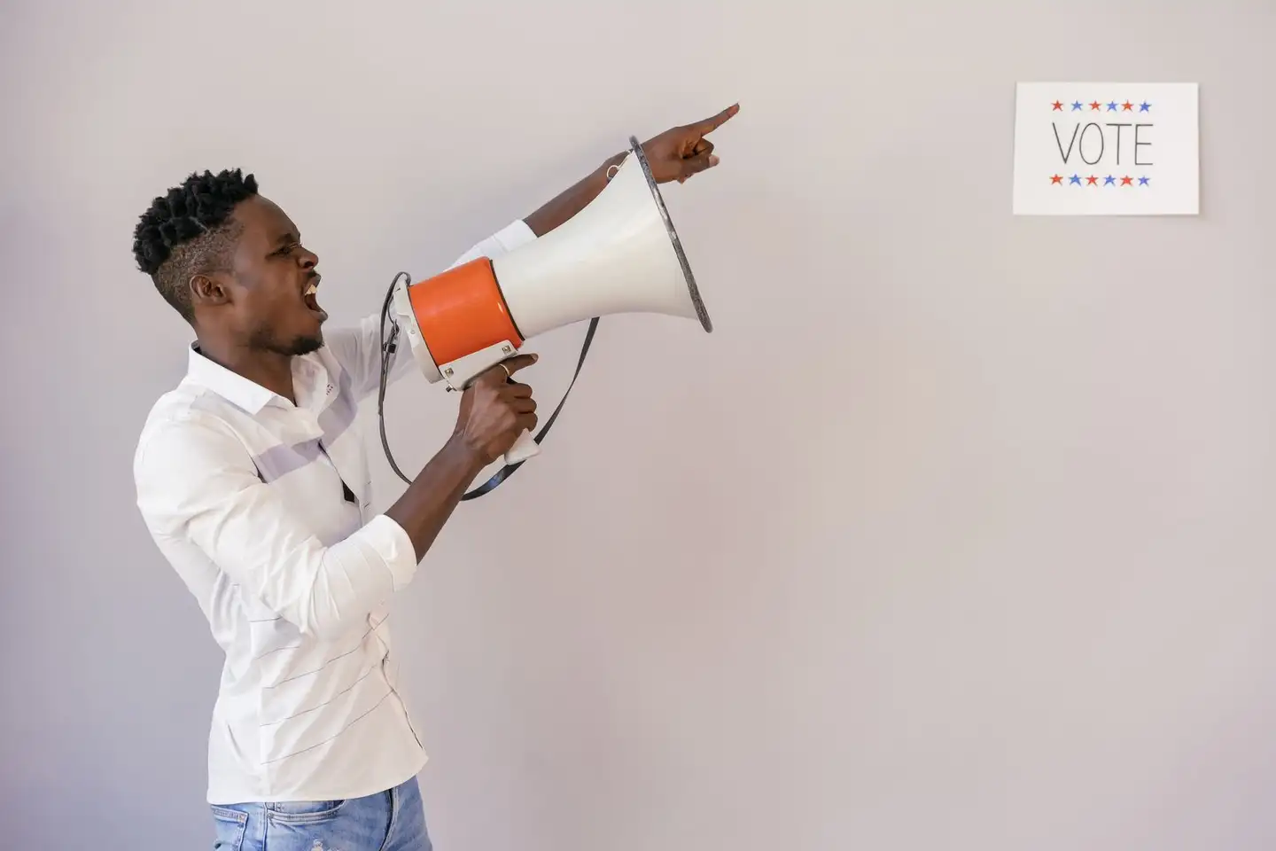 A man using a megaphone beside a vote sign to encourage people to vote
