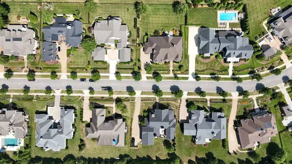 An aerial view of homes and tree-lined streets in a suburban neighborhood.