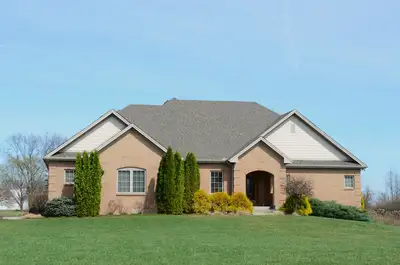 A modest suburban brick house with a well-kept lawn