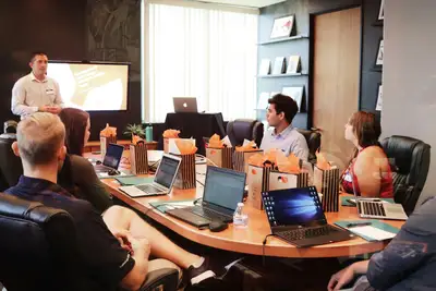 A presenter leading a training session for a group seated with laptops