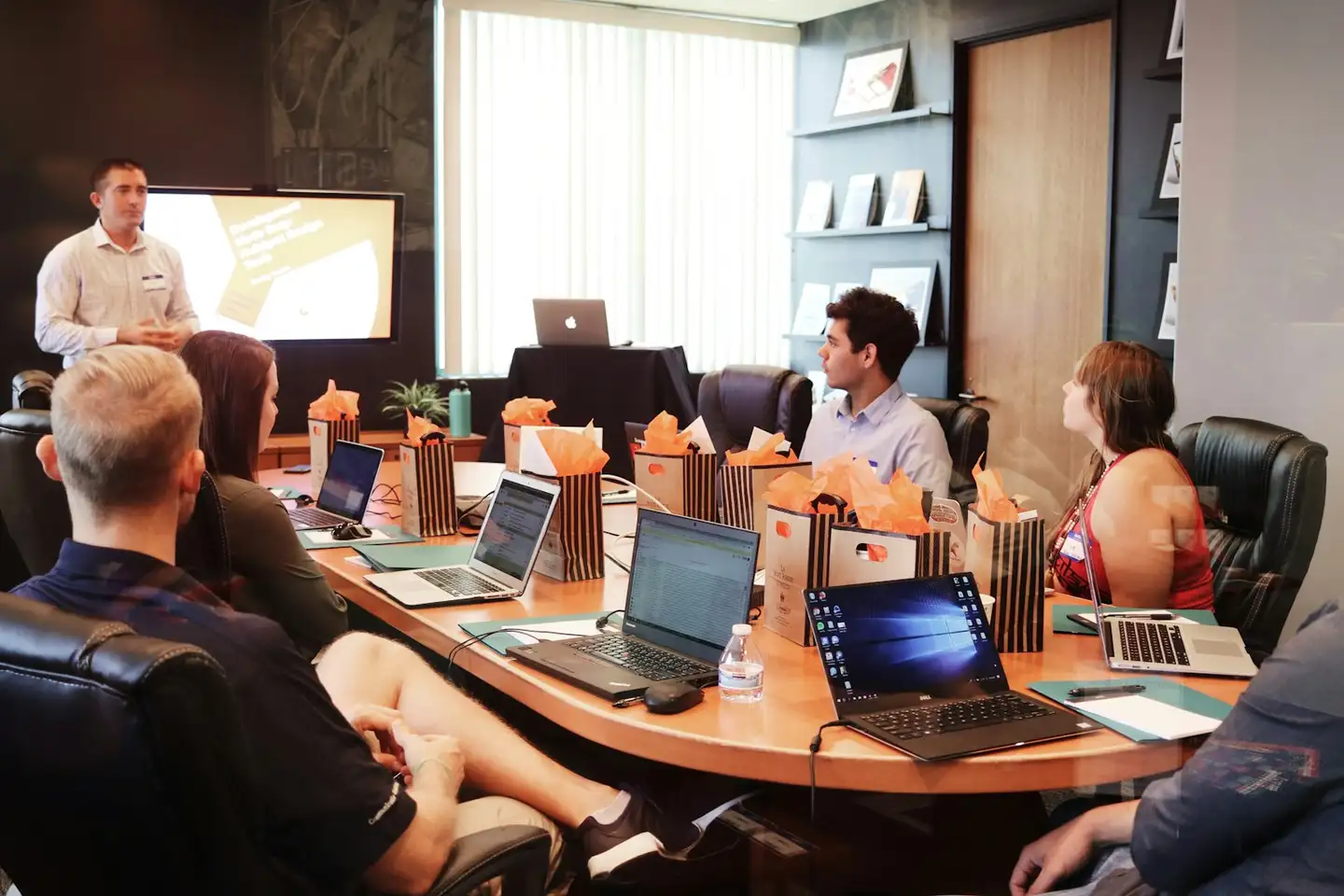 A presenter leading a training session for a group seated with laptops