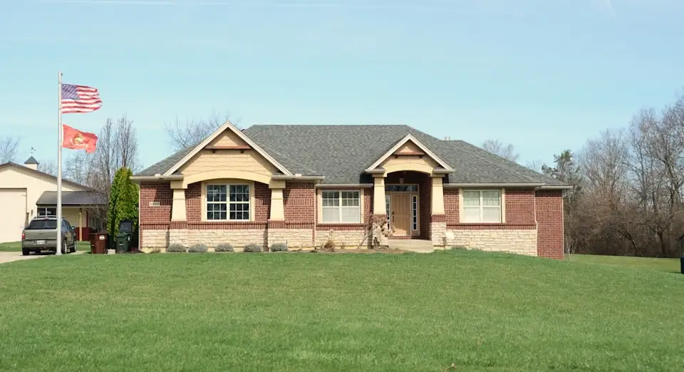 A single-family brick house set behind a wide green front lawn.