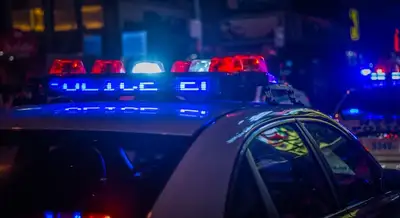 A police car's lights flash in the night, red and blue