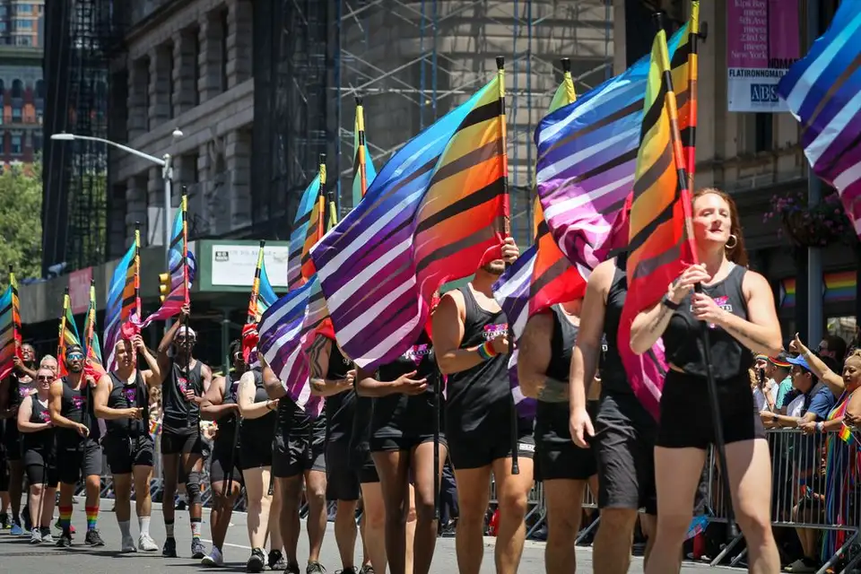 Marchers carry rainbow Pride flags through a city street during an NYC Pride parade.