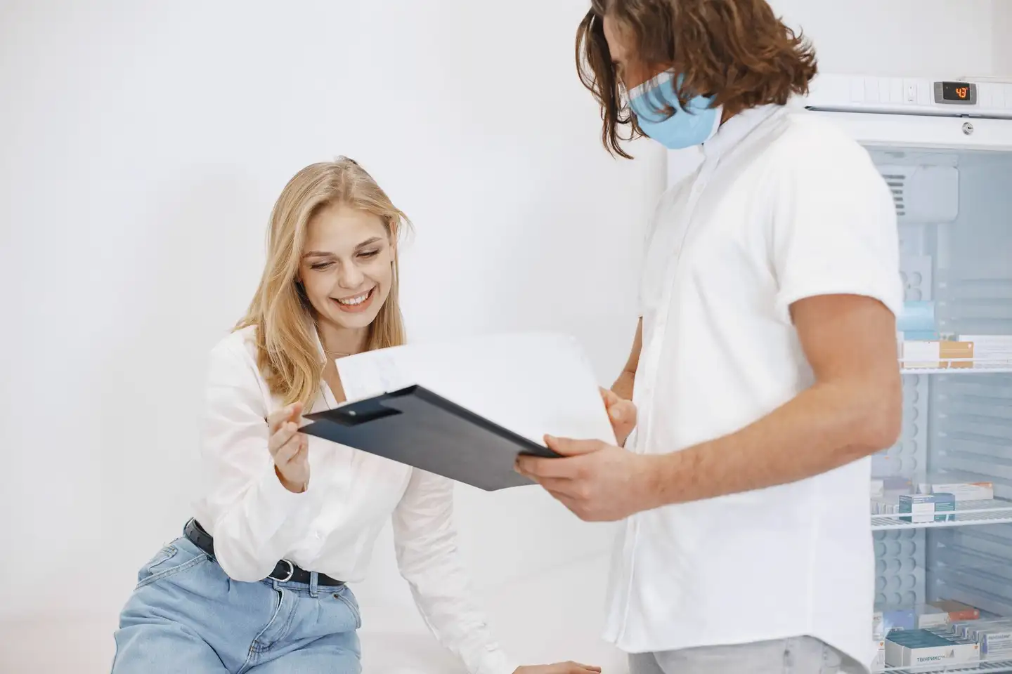 A patient reviewing her medical chart with a clinician in an exam room