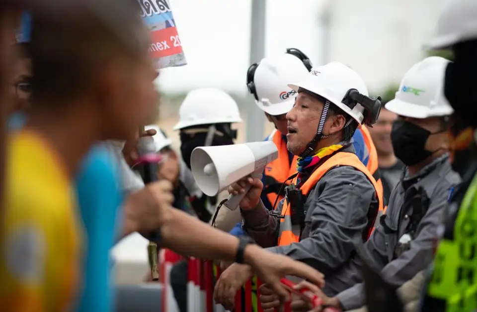 Workers raise a megaphone and signs during a labor protest.