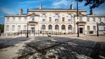 A stately neoclassical town hall in warm stone under a bright blue sky