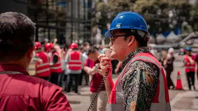 A worker in a hard hat addressing coworkers through a megaphone