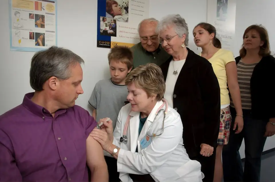A nurse gives a man an injection as his family looks on at a community clinic.
