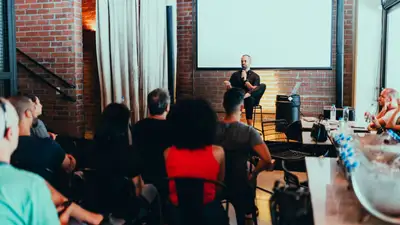 A speaker addressing a diverse audience at an indoor seminar