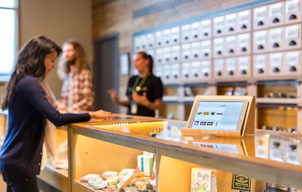 Budtenders assist customers at the counter of a cannabis dispensary.